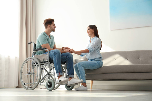 Young woman with man in wheelchair indoors - Foto, Imagem