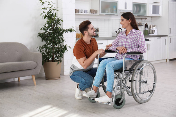 Young man with woman in wheelchair indoors - Foto, Imagen