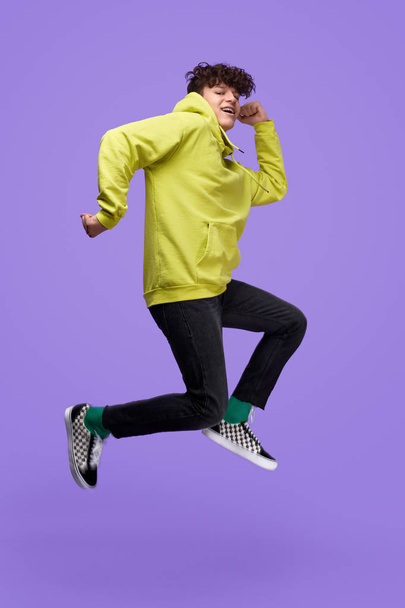 Teenager jumping high on purple background - Photo, Image