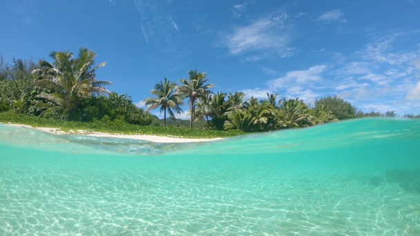 Zeitlupe, halb unter Wasser: Beliebter weißer Sandstrand auf abgelegener tropischer Insel bleibt in der touristischen Nebensaison leer, trotz des atemberaubenden Blicks auf das glasige Meerwasser und die üppigen Palmen. - Filmmaterial, Video