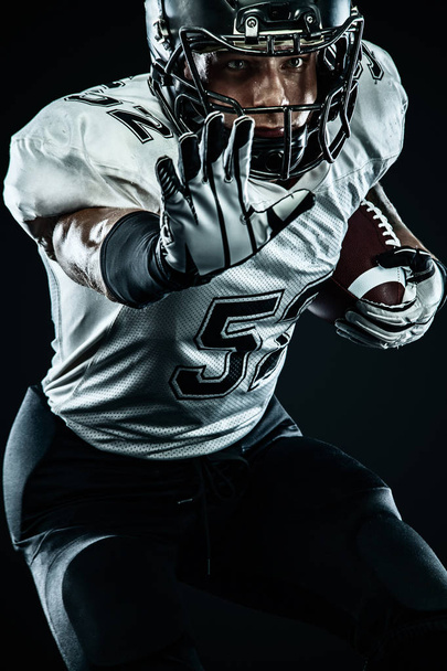 American Football Sportler mit Helm isoliert Lauf in Aktion auf schwarzem Hintergrund. Sport und Motivation Tapete. Mannschaftssport, - Foto, Bild