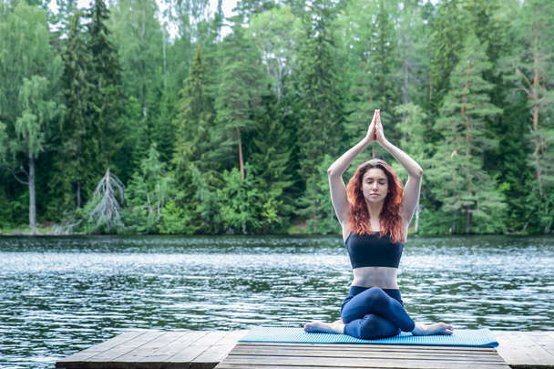 Молодая девушка практикует йогу на природе на озере. Самка хапа
 - Фото, изображение