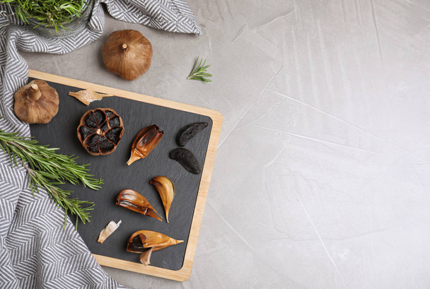 Flat lay composition with black garlic and space for text on grey table - Foto, Imagem