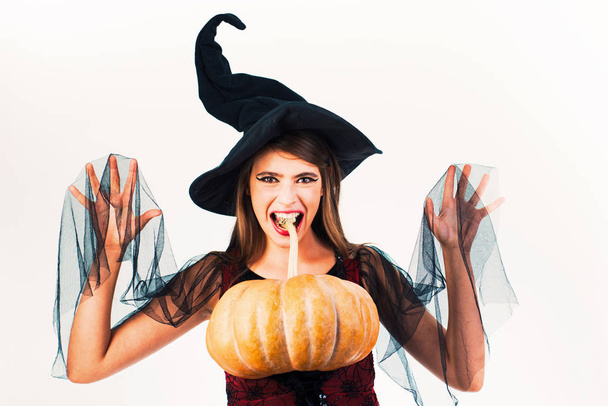 Beauty Woman posing with Pumpkin and Halloween hat. Attractive model girl in Halloween costume. Halloween concept. - Fotó, kép