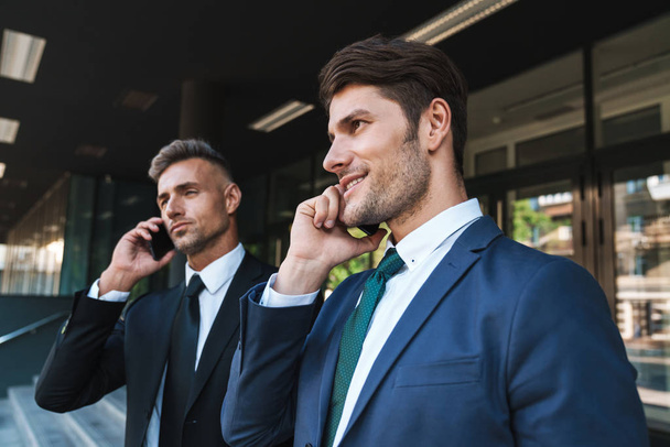 Image of confident businessmen partners standing outside office  - Photo, image