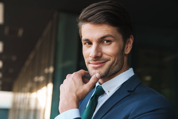 Photo closeup of attractive businessman touching his chin while  - Фото, зображення