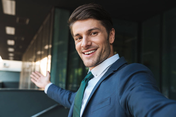 Photo of beautiful businessman smiling at camera and taking self - Foto, Bild
