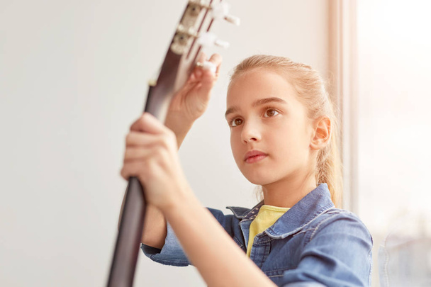 Focused girl tuning guitar - Foto, Bild
