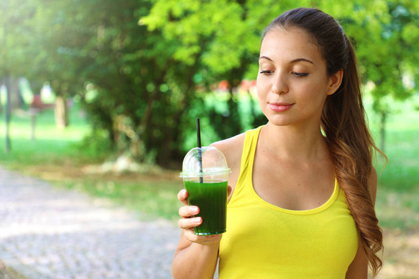 Sporty woman looking at her green detox smoothie with copy space - Foto, imagen