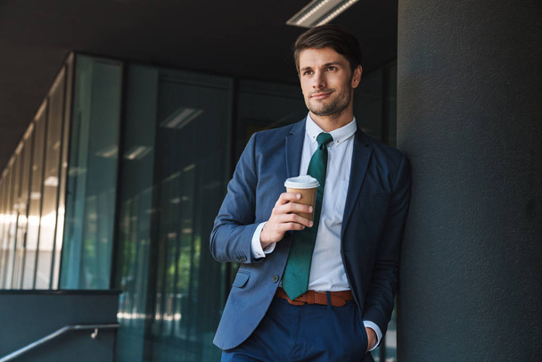 Photo of young businessman drinking takeaway coffee from paper c - Photo, image