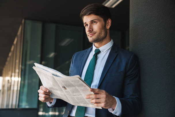 Photo of confident businessman reading newspaper while standing  - Fotó, kép