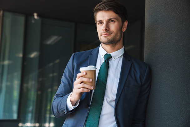 Photo of confident businessman drinking takeaway coffee from pap - Фото, изображение