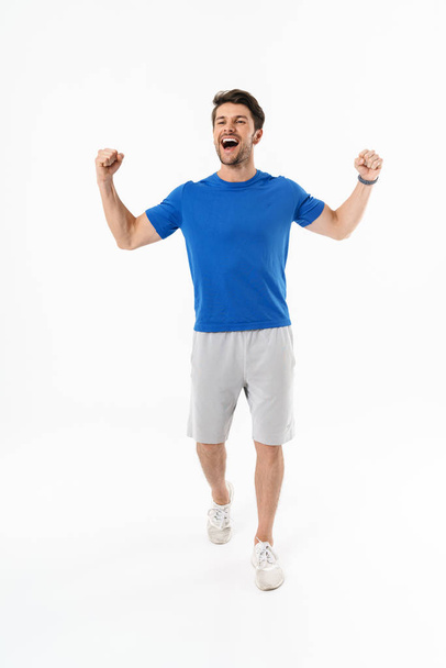 Full length photo of happy man in shorts and t-shirt screaming and rejoicing with clenching fists - Φωτογραφία, εικόνα