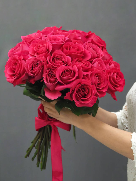 ramo de rosas rojas en sus manos
 - Foto, Imagen