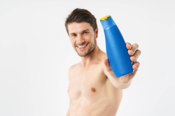 Photo closeup of joyful naked man smiling and holding shampoo bo - Foto, immagini
