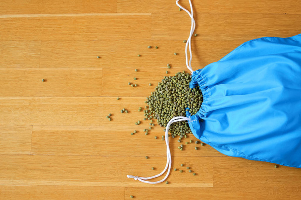 Zelený Mungo fazole v modrém opakovaně použitelném balení na dřevěném podkladu. Kopírovat místo - Fotografie, Obrázek