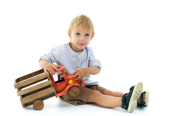 Little boy is playing with a wooden car. - Foto, Imagen