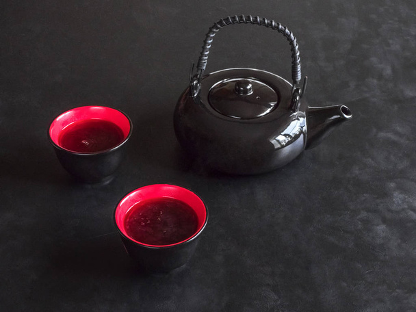 deux tasses de thé rouge et théière noire sur table noire
 - Photo, image