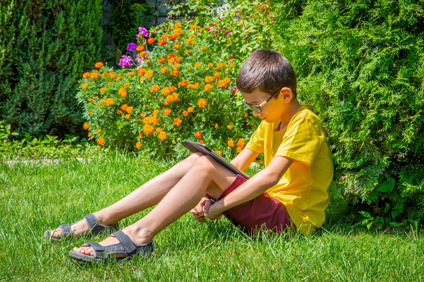 Молодий хлопчик дивиться фільми на планшеті в одному парку
 - Фото, зображення