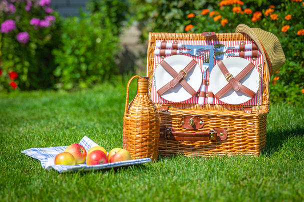 公園の緑の日当たりの良い芝生のピクニックバスケット - 写真・画像