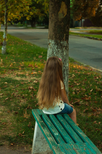 Petite fille aux longs cheveux blonds dans un T-shirt blanc sur fond de nature
. - Photo, image
