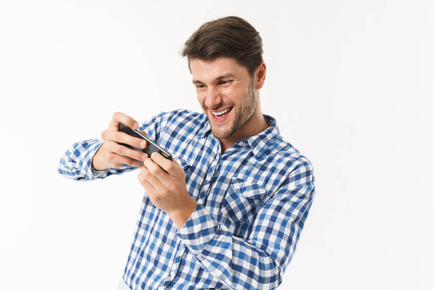 Photo of excited man in casual shirt playing video game on cellphone - Fotografie, Obrázek