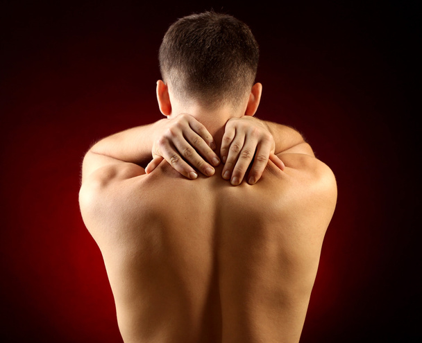 Young man with neck pain, on red background - Фото, изображение