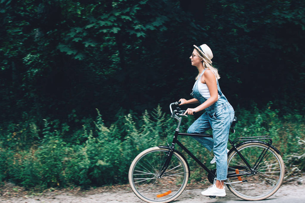 Beautiful teenage girl riding bicycle through the forest or park. - Foto, Imagem