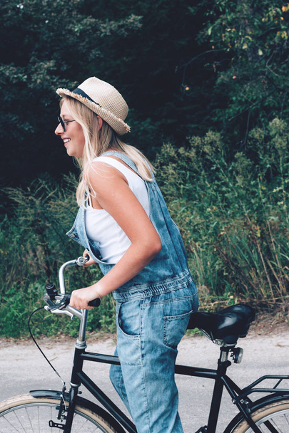 Piękna Nastoletnia dziewczyna jeździ rowerem przez las lub Park. - Zdjęcie, obraz