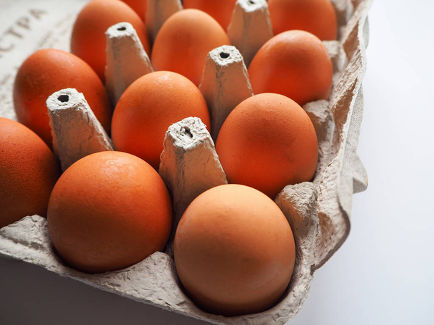 Pack of brown fresh raw chicken eggs in a white carton egg box on a white background close up.  - Photo, Image
