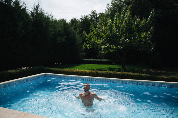 junger Mann schwimmt im Schwimmbad im Garten. Gesunder Lebensstil. Seitenansicht - Foto, Bild