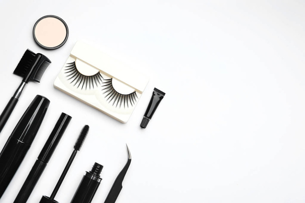 Composition with false eyelashes and other makeup products on white background, top view - Foto, imagen