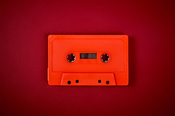 Oranje audio cassette op de donker rode achtergrond - Foto, afbeelding