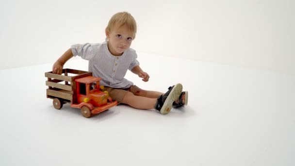 Little boy is playing with a wooden car. - Felvétel, videó