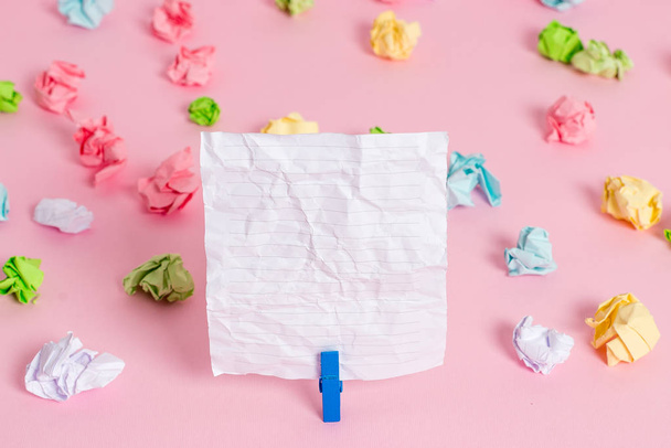 Colored crumpled sheets placed around the empty rectangle square shaped reminder note in the pink background. Office supplies, blank paper pinned by a fastener. - 写真・画像