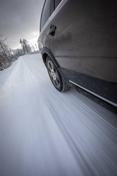 Fast moving car on a winter alpine snowy road - Фото, изображение
