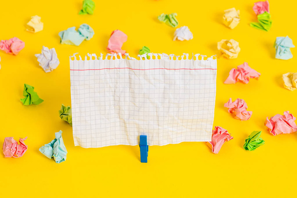 Colored crumpled sheets placed around the empty rectangle square shaped reminder note in the yellow background. Office supplies, blank paper pinned by a fastener. - Fotografie, Obrázek