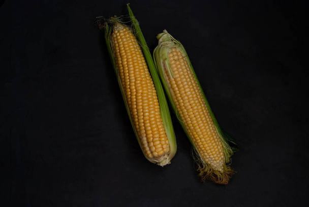 Yellow sweet raw corn on a black background.  - Фото, изображение