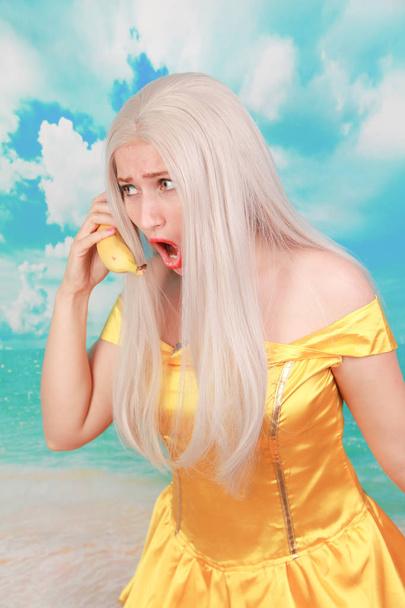 Divertido triste chica infeliz con teléfono de plátano sobre fondo azul
. - Foto, imagen