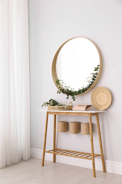 Round mirror and table with accessories near white wall. Modern interior design - Photo, image