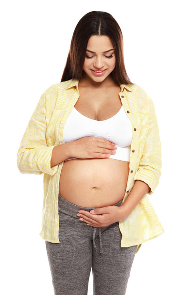 Portret van mooie jonge zwangere vrouw in shirt op witte achtergrond - Foto, afbeelding