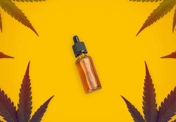 feuilles de cannabis sativa formant un cadre et bouteille d'huile de cannabis CBD isolé sur fond orange
 - Photo, image