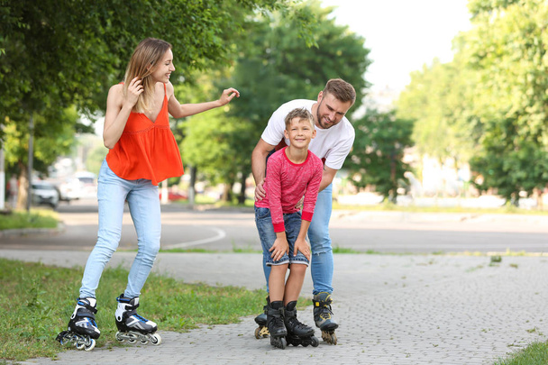 Young happy family roller skating on city street - Valokuva, kuva