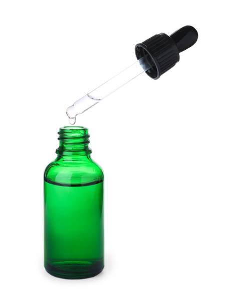 Huile essentielle goutte à goutte de la pipette dans une bouteille isolée sur blanc
 - Photo, image