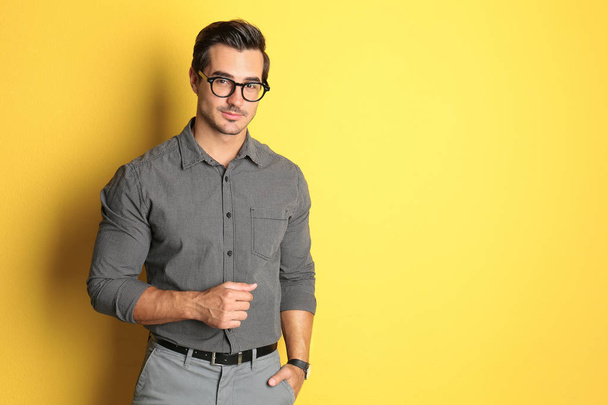 Young male teacher with glasses on yellow background. Space for text - 写真・画像