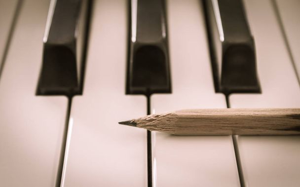 Stará tužka na bílé klávesy elektrického klavíru v horizontálním zobrazení - Fotografie, Obrázek