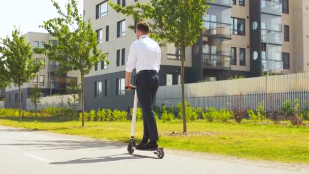 young businessman riding electric scooter outdoors - Video, Çekim