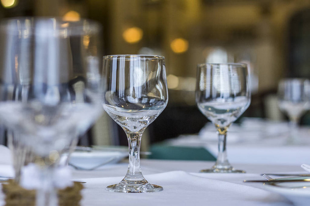 Glazen kommen op tafel met wit tafellaken en bestek op tafel. - Foto, afbeelding