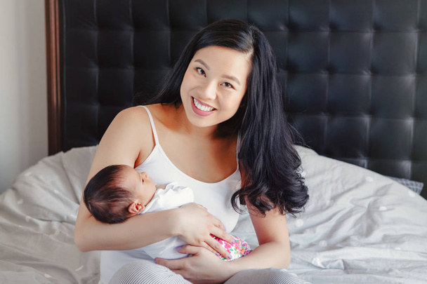 Porträt der schönen lächelnden chinesischen asiatischen Mutter mit süßen entzückenden neugeborenen Säugling Sohn Tochter. glückliche Familie im Schlafzimmer. Lebensstil zu Hause authentische natürliche Moment. Muttertag. - Foto, Bild