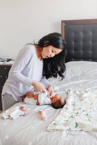 Kínai ázsiai elfoglalt anya változó pelenkát újszülött csecsemő fia lánya. Home életmód hiteles természetes családi pillanat. Anyák napja. Kihívások és nehézségek az anyaság. - Fotó, kép